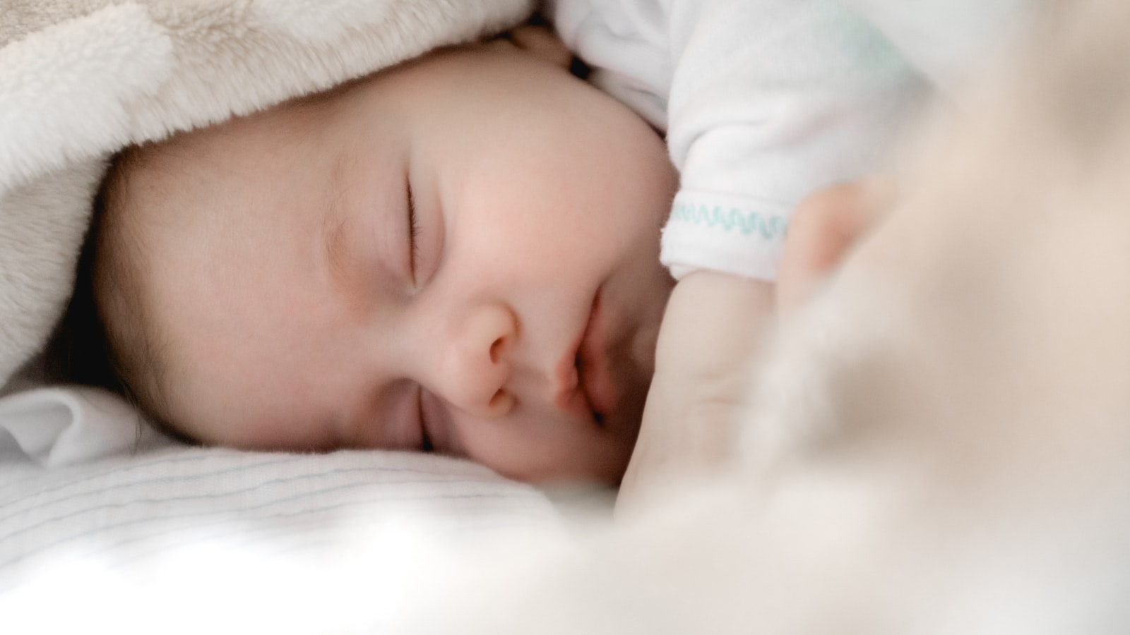 A packed overnight bag with baby clothes resting beside the front door